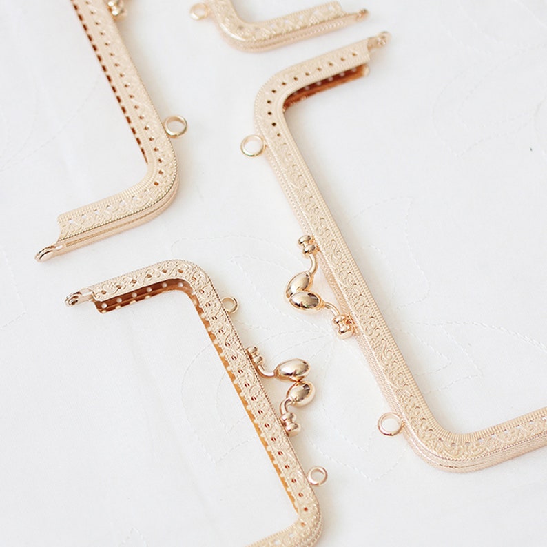May include: Four gold-toned metal purse frames with intricate designs. The frames are open and ready to be used for a DIY project.