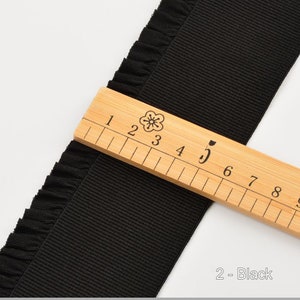 May include: Black ruffled trim ribbon with a ruler showing 5 inches. The ribbon is 2 inches wide.