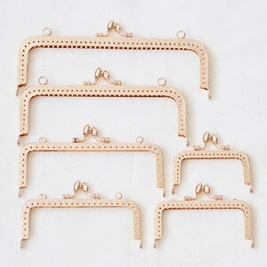 May include: Set of five gold-toned metal purse frames with decorative details. The frames are different sizes and are arranged in a row from largest to smallest.