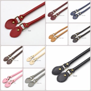 May include: Assortment of leather handbag handles in various colours, including red, burgundy, yellow, light coffee, black, pink, and grey. Each handle has two metal loops with a decorative design.