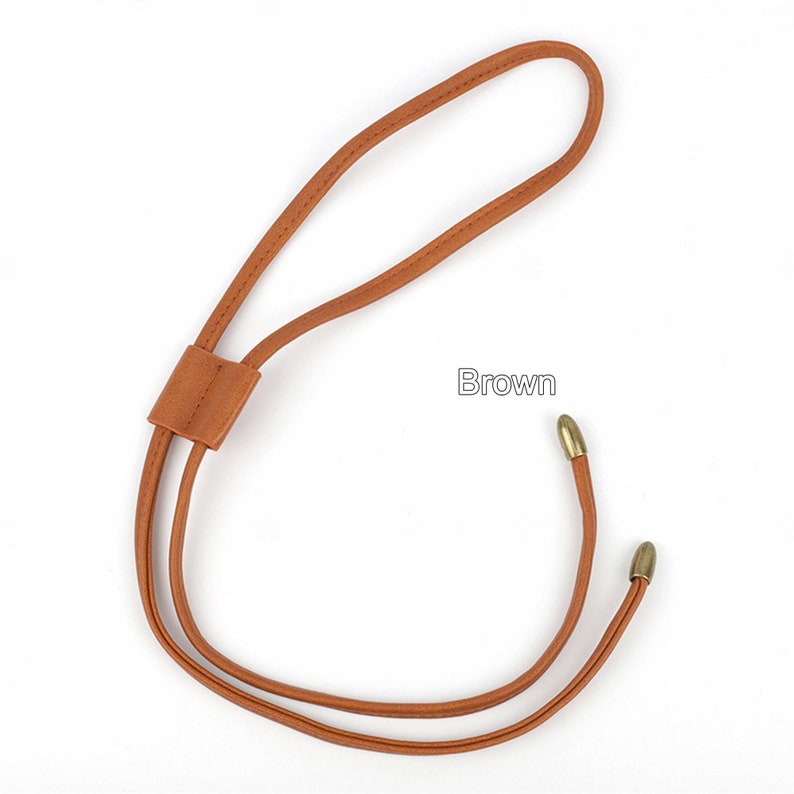 May include: Brown leather cord with gold metal tips. The cord has a loop at the top and is tied together at the bottom.