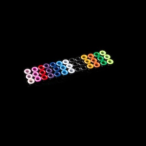 Puede incluir: Surtido de ojales metálicos de colores en forma de arcoíris sobre un fondo negro.