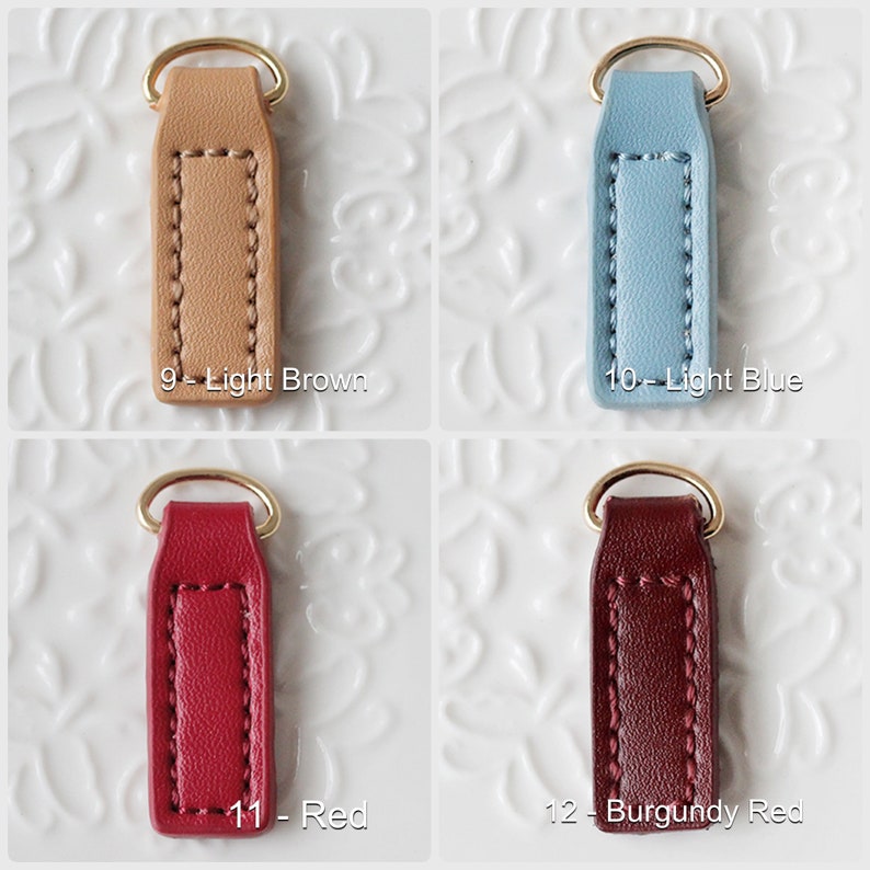Op de afbeelding: Vier leren sleutelhangers in lichtbruin, lichtblauw, rood en bordeaux. Elke sleutelhanger heeft een goudkleurige ring en is gelabeld met een nummer en kleurnaam. De sleutelhangers zijn gestikt en rechthoekig.