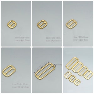 May include: Five gold metal slider buckles in different sizes. The buckles are rectangular with a rounded edge and have two holes on each side. The inner width of the buckles is 13mm, 16mm, 20mm, and 26mm. The inner height of the buckles is 5.5mm, 5.5mm, 6mm, and 7.2mm.