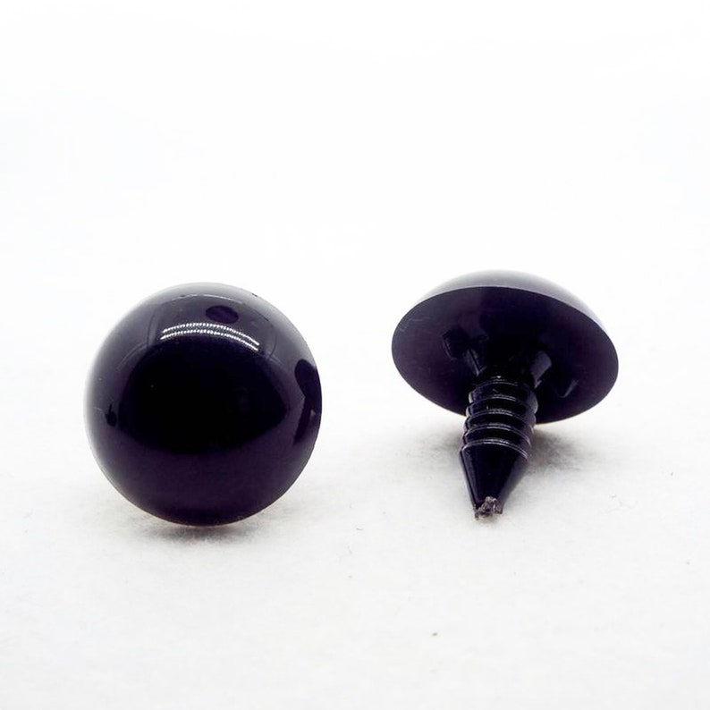 May include: Two black plastic safety eyes with a screw back. The eyes are round and have a shiny finish.