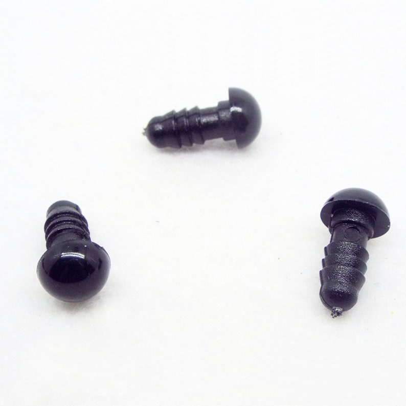 May include: Three black plastic safety eyes with a screw-on back. The eyes are round and have a glossy finish.