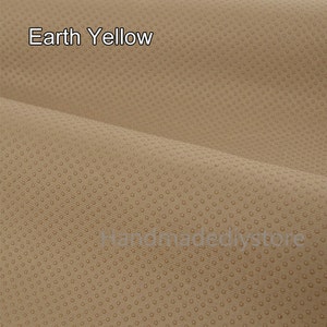 May include: A close-up of a textured fabric in a light brown color with a subtle pattern of small dots. The fabric is called "Earth Yellow" and is labeled in both English and Chinese.