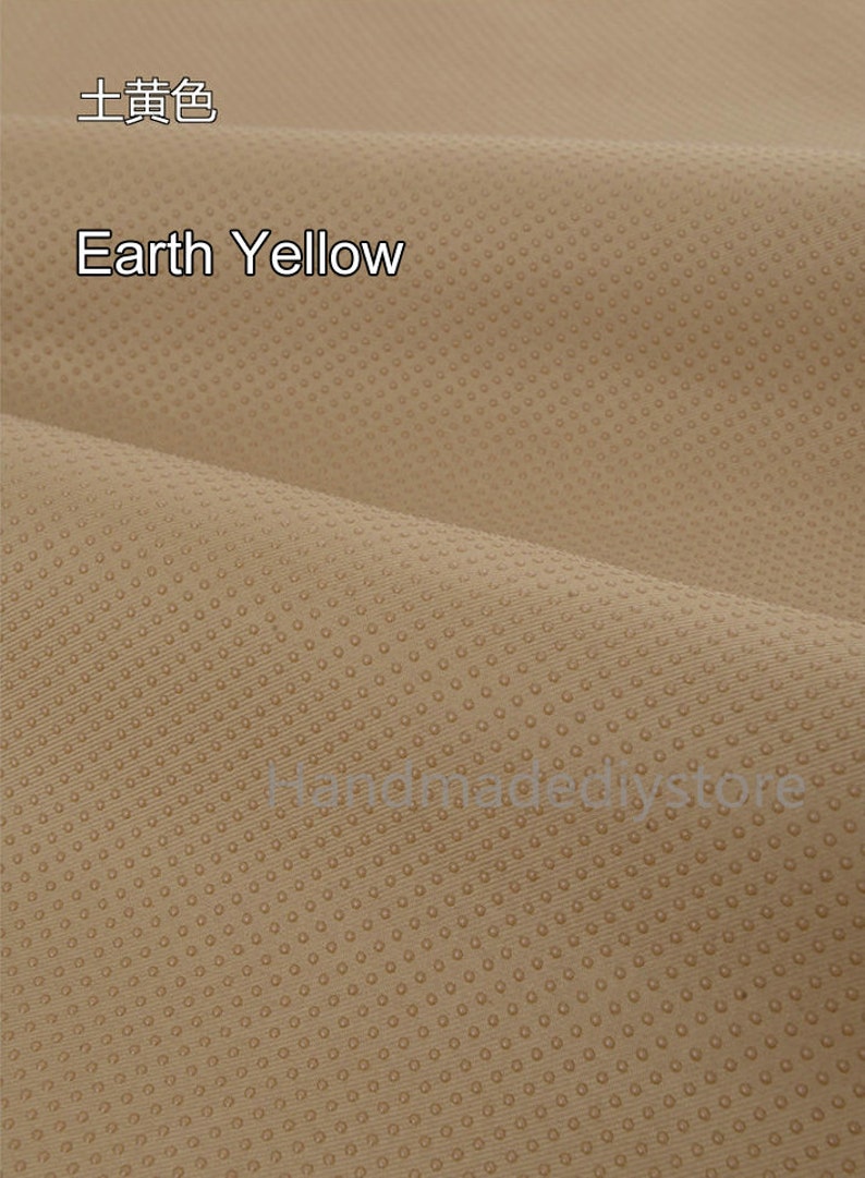 May include: A close-up of a textured fabric in a light brown color with a subtle pattern of small dots. The fabric is called "Earth Yellow" and is labeled in both English and Chinese.