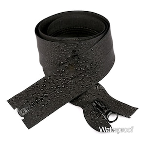 Könnte beinhalten: Schwarzes, wasserdichtes Reißverschlussband mit Wassertropfen auf der Oberfläche. Das Reißverschlussband ist aufgerollt und hat einen Schieber mit einem Metallring. Der Text "Waterproof" ist in der unteren rechten Ecke des Bildes gedruckt.