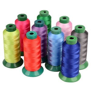 Puede incluir: Una colección de coloridas bobinas de hilo. El hilo está enrollado alrededor de bases de plástico verde. Los colores incluyen rojo, rosa, verde, morado, azul y gris. Las bobinas están dispuestas en un patrón circular, con el hilo visible.