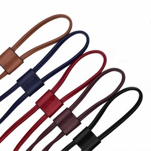 May include: Five leather cords in different colors: brown, navy blue, red, burgundy, and black. Each cord has a loop at one end and a knotted section at the other.