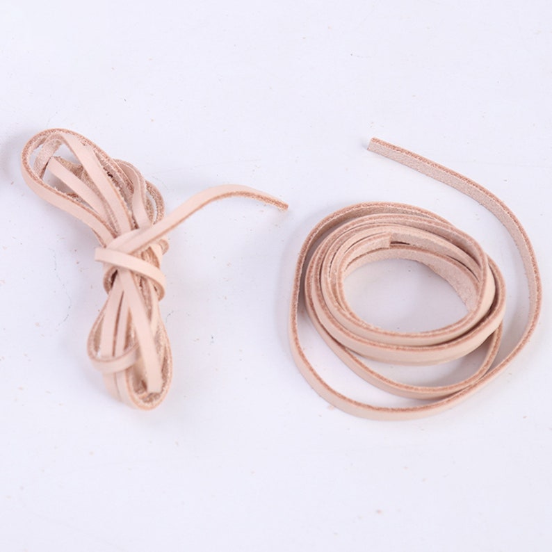 May include: Two spools of light brown leather cord. One spool is coiled and the other is loose.