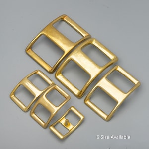 Könnte beinhalten: Sechs goldfarbene Metallschnallen in verschiedenen Größen. Die Schnallen sind für Lederriemen konzipiert und haben eine rechteckige Form mit zwei Löchern. Der Text "6 Size Available" ist am unteren Rand des Bildes sichtbar.