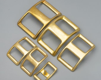 May include: Six gold-toned metal buckles of different sizes. The buckles are designed for leather straps and have a rectangular shape with two holes. The text "6 Size Available" is visible at the bottom of the image.