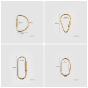 Op de afbeelding: Vier verschillende stijlen van gouden sleutelhangers met afmetingen in millimeters. De sleutelhangers zijn allemaal van metaal en hebben een eenvoudig ontwerp.