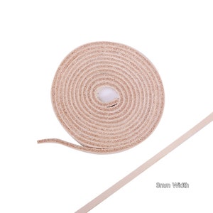 May include: A roll of 3mm wide natural leather cord. The cord is rolled up and the end is extended to show the width.