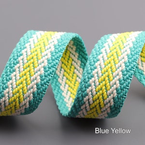 Pode incluir: Um close-up de uma fita tecida azul e amarela. A fita &eacute; feita de um material macio e texturizado e tem um brilho sutil.