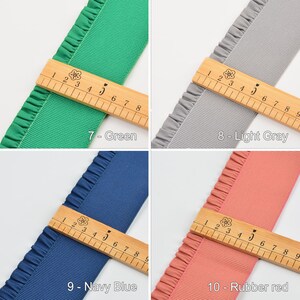 May include: Four different colors of ruffled ribbon with a wooden ruler measuring 9 inches. The colors are green, light gray, navy blue, and rubber red.