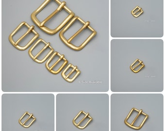 Puede incluir: Seis tamaños diferentes de hebillas de cinturón de metal dorado. Las hebillas están dispuestas en orden de tamaño, con la hebilla más grande en la parte superior y la más pequeña en la parte inferior. El texto "6 Size Available" está impreso debajo de las hebillas.