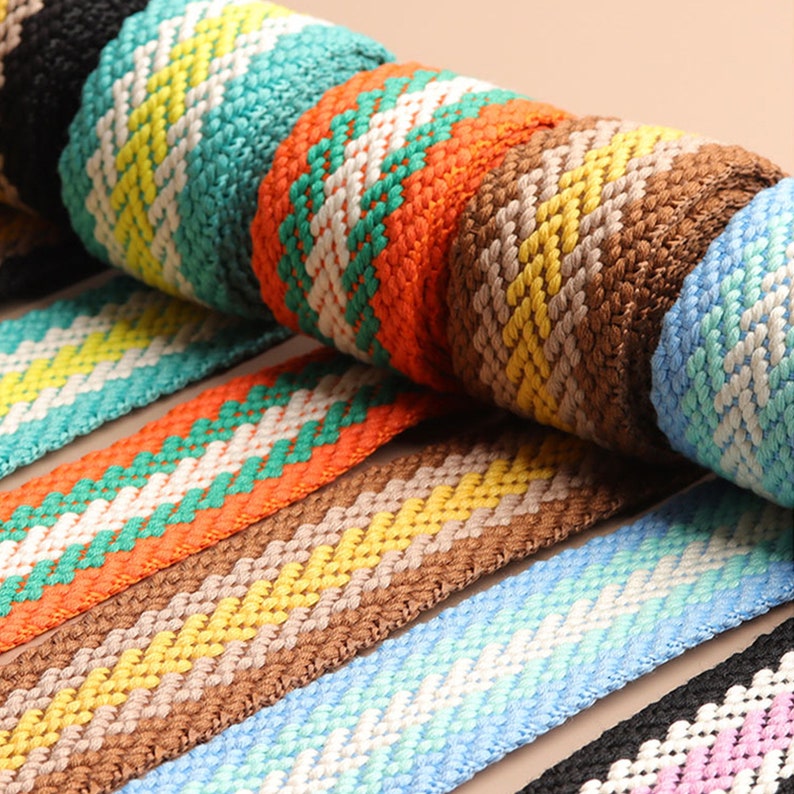 Pode incluir: Conjunto de fitas tecidas coloridas com padr&otilde;es geom&eacute;tricos em preto, branco, laranja, amarelo, verde, azul e marrom.