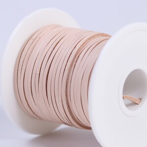 May include: A spool of light pink leather cord, wound around a white plastic spool.