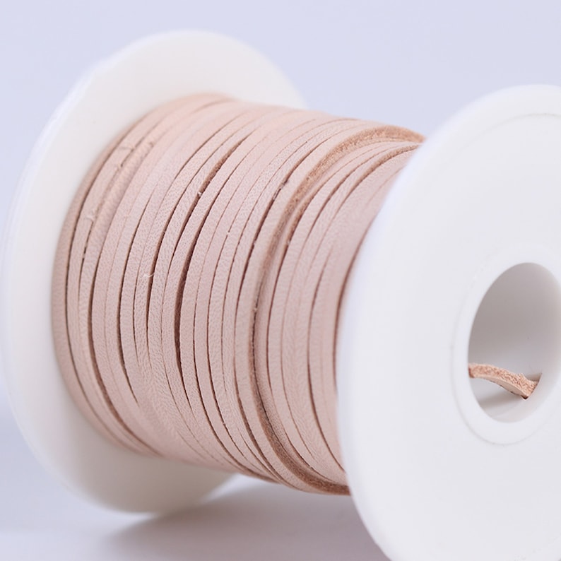 May include: A spool of light pink leather cord, wound around a white plastic spool.