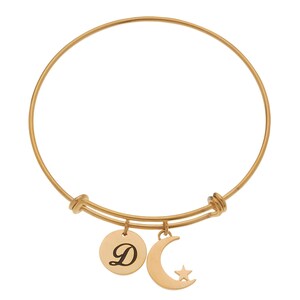 May include: Gold-toned bangle bracelet with a charm of a crescent moon with a star and a round charm with the letter D.