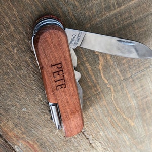 May include: A pocket knife with a brown wooden handle and a stainless steel blade. The knife has a variety of tools and is engraved with the name "Pete".