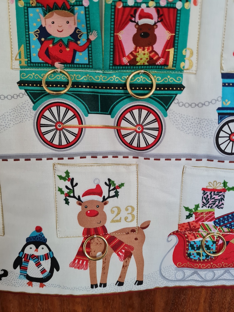 Adventskalender mit Taschen zum füllen und Ringe für kleine Päckchen. Der Kalender ist ein Motiv aus Eisenbahn mit Weihnachtsmann und Wichtel.
