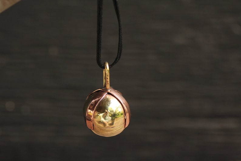 Brass Ball Pendant with a Copper X across the top on a Black Leather cord.