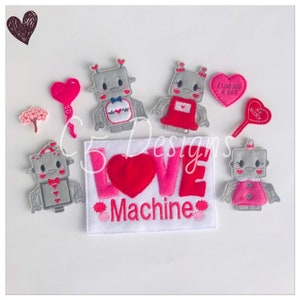 May include: A felt craft set featuring four robot characters with hearts and the words "LOVE MACHINE" in pink and red. The robots are gray with pink and red accents.