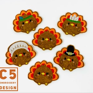 May include: Five felt applique patches of Thanksgiving turkeys with different hats. The turkeys are brown with orange and red feathers. The hats include a pilgrim hat, a chef's hat, a Native American headdress, and two different styles of pilgrim hats.