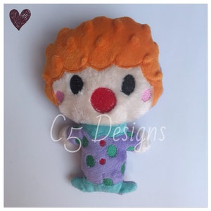 May include: A plush toy clown with orange hair, a white face, a red nose, and a purple and green polka dot outfit.