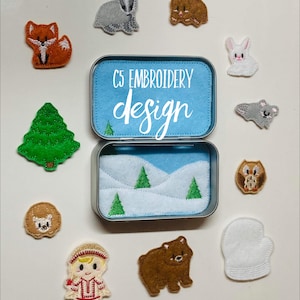 May include: A tin with a blue lid that says "C5 Embroidery Design" and a white interior with a snowy landscape and green trees. The tin is surrounded by felt appliques of various animals and objects, including a fox, a bear, a badger, a rabbit, a hedgehog, an owl, a mitten, a girl in a winter coat, and a Christmas tree.