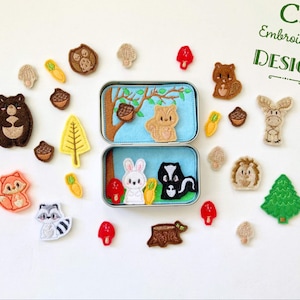 Könnte beinhalten: Ein Set aus Filz-Stickmotiven mit Tier- und Naturmotiven, darunter ein Bär, ein Fuchs, ein Waschbär, ein Eichhörnchen, ein Stinktier, ein Igel, ein Pilz, ein Baum und eine Eichel. Die Motive sind auf einem weißen Hintergrund angeordnet, mit dem Text "C5 Embroidery Design" in der oberen rechten Ecke.