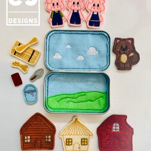 May include: A felt play set in a tin box with three pink pigs, a brown wolf, a wooden house, a straw house, a brick house, a bucket, a shovel, a broom, and a stick of wood. The set is designed for children to play with and learn about the story of the Three Little Pigs.