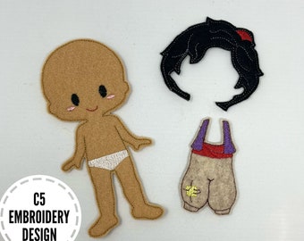 May include: A felt doll with brown skin, a white undergarment, and a set of clothing including pants and a vest. The doll has black hair and a smiling face. The doll is designed for use with a felt doll dress-up set.