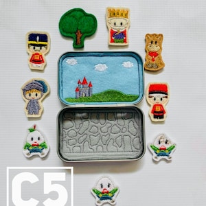 May include: A set of felt characters in a tin box. The characters include a king, a queen, a soldier, a tree, and a horse. The tin box has a blue felt interior with a castle and clouds embroidered on it.