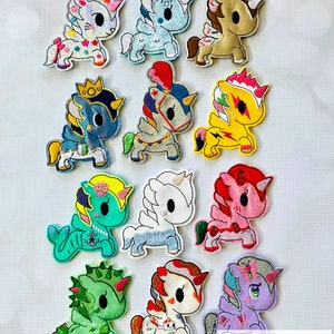 May include: A set of 12 embroidered iron-on patches featuring colorful unicorn designs. The patches are all different colors and have various details, including glitter, sequins, and 3D elements. The patches are labeled "EXCLUSIVE SET #53".