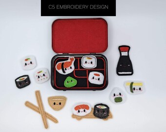 May include: A set of embroidered sushi and Japanese food items, including a sushi roll, a bowl of rice, chopsticks, and a bottle of soy sauce. The items are arranged in a small metal tin with a red interior. The text "C5 EMBROIDERY DESIGN" is printed on the top of the tin.