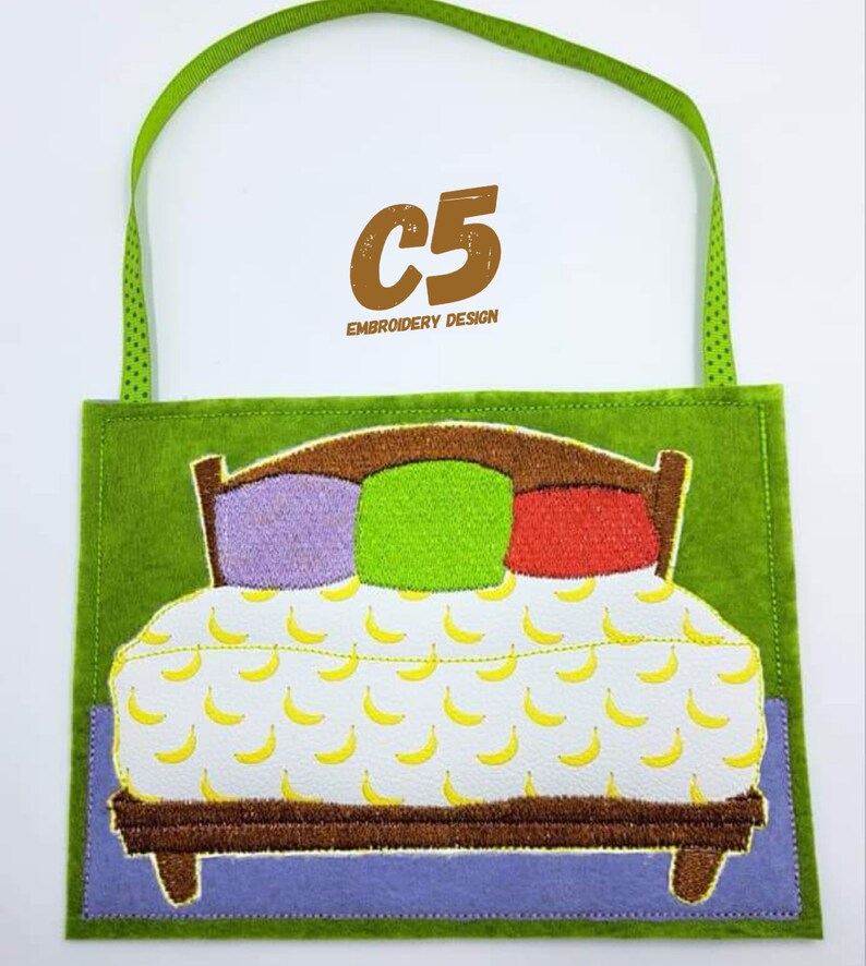 May include: A green felt appliqu&eacute; with a brown bed with three pillows, one purple, one green, and one red. The bed has a white sheet with a yellow banana pattern. The appliqu&eacute; has a green felt loop for hanging. The text "C5 EMBROIDERY DESIGN" is in brown text at the top.