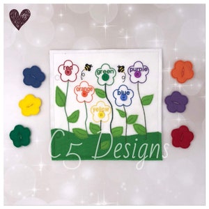 May include: A felt color matching activity featuring a white square with embroidered flowers labeled with colors. Each flower has a button center and a matching felt flower. The text "C5 Designs" is at the bottom.