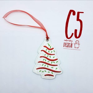 May include: White felt Christmas tree ornament with red and green embroidery. The ornament has a red ribbon attached for hanging. The text "C5 embroidery DESIGN" is visible in the image.