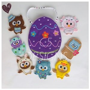 Puede incluir: Un conjunto de siete marionetas de dedos de fieltro con búhos vestidos con diferentes disfraces. Las marionetas están dispuestas alrededor de un huevo de fieltro morado con un asa blanca. El huevo tiene un diseño de líneas onduladas y está decorado con flores de colores. El texto "C5 Designs" está bordado en el huevo.