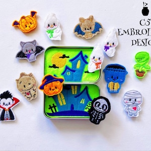 May include: A set of 10 Halloween-themed felt appliques, including a ghost, a vampire, a mummy, a Frankenstein, a witch, a pumpkin, a bat, a spider, a haunted house, and a plant. The appliques are arranged around a small tin box with a green background and a blue haunted house design. The text "C5 Embroidery Design" is printed on a white background.