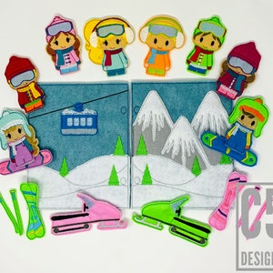 May include: Felt finger puppets of people wearing winter clothing, including hats, scarves, and jackets. The puppets are arranged around a felt scene of a snowy mountain landscape with a ski lift, a snowmobile, and a snowboard.
