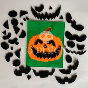 May include: A felt pumpkin puzzle with orange felt pumpkin and black felt pieces to create a jack-o'-lantern face. The pieces are scattered around the pumpkin.