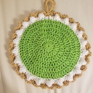 May include: A green crocheted pot holder with a white and brown crocheted border and a loop handle.