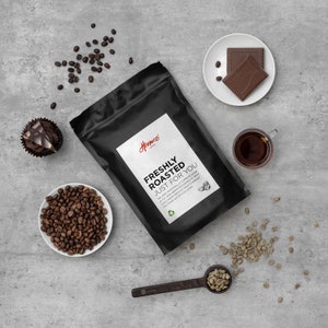 K&ouml;nnte beinhalten: Ein schwarzer Beutel Hormozi-Kaffee mit dem Text "FRESHLY ROASTED JUST FOR YOU". Das Bild zeigt auch Kaffeebohnen, eine Tasse Kaffee, einen Cupcake und zwei Schokoladenquadrate auf einem wei&szlig;en Teller. Ein L&ouml;ffel h&auml;lt gr&uuml;ne Kaffeebohnen.