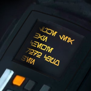 Könnte beinhalten: Ein schwarzes Gerät mit einem gelben digitalen Display, das den Text "V11K", "EKI", "HEVO1M", "7272" und "EVI" anzeigt.